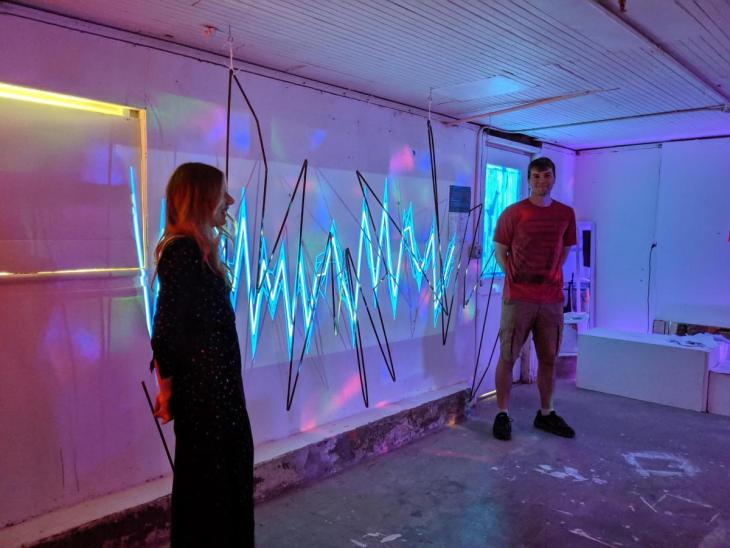 Photo of Paris Meyers and Nick Bira standing in front of artwork.